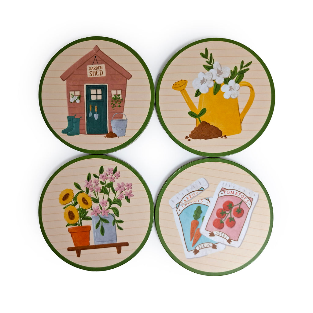 Top-down view of a set of four round cork coasters, each with a green edge and a unique garden-themed illustration on a light wood-effect background. Designs include a garden shed, a yellow watering can with white flowers, potted sunflowers and pink flowers on a shelf, and seed packets for carrots and tomatoes.