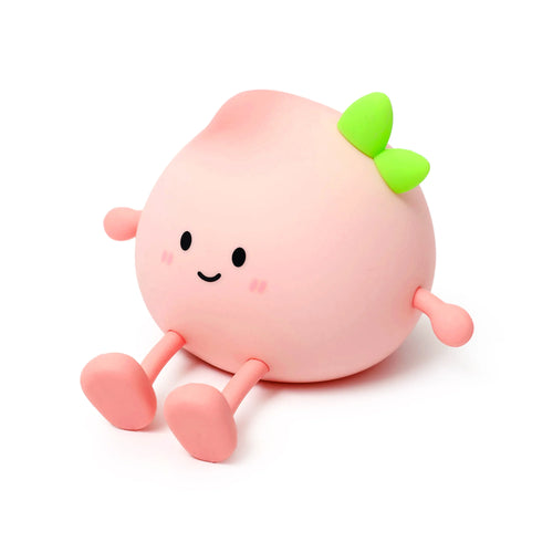 Front view of a Foodiemals Peach sleep lamp night light, a pale pink, peach-shaped character with a smiling cartoon face, green leaves on top, and small arms and legs, sitting on a white background.