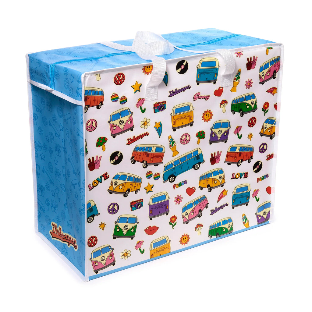 Angled view of a white and blue laundry and storage bag, featuring a retro Volkswagen VW T1 Camper Bus pattern. The colourful design includes camper vans, peace signs, flowers, and groovy motifs, with a blue zipped top and white carry handles.