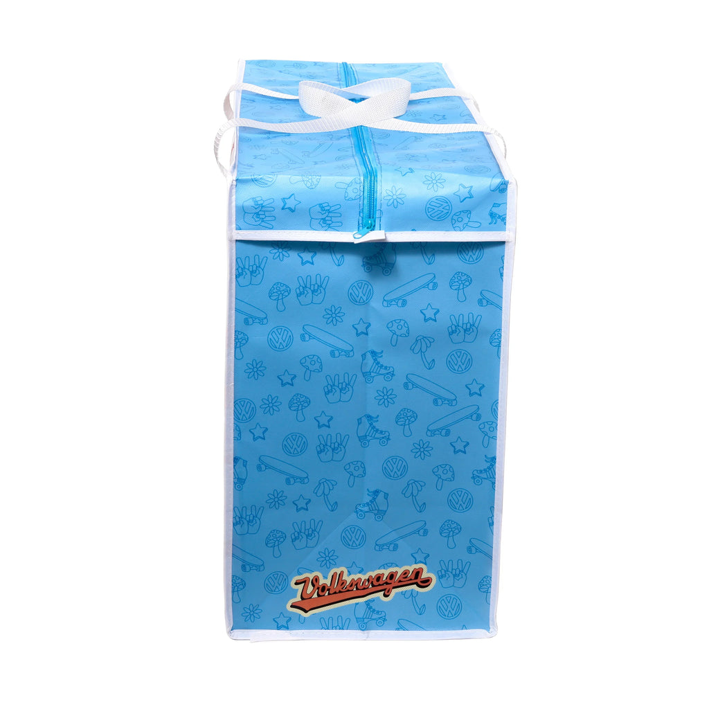 Angled front view of a blue laundry and storage bag with a repeating retro pattern of peace signs, mushrooms, skateboards, roller skates, and VW logo emblems. It features an orange Volkswagen text logo, white fabric handles, and a blue zip closure.