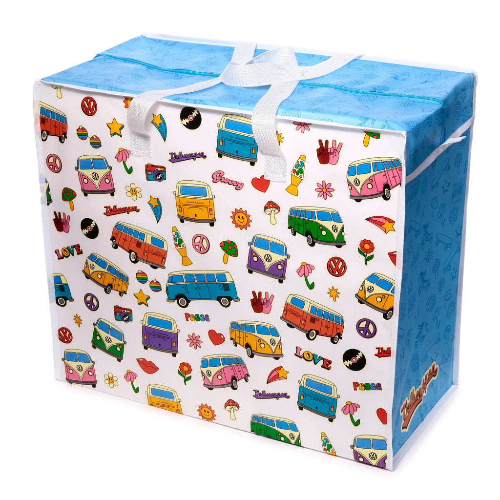Angled view of a white laundry and storage bag, featuring a colourful retro Volkswagen camper van pattern, peace signs, flowers, and other groovy illustrations. It has a blue zippered top and white carrying handles.
