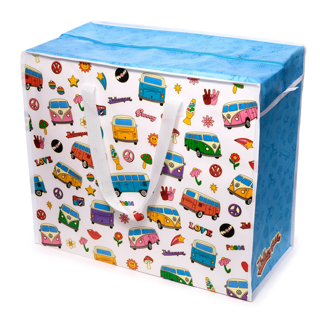 Angled view of a white laundry and storage bag with a colourful retro Volkswagen T1 Camper Bus print, featuring peace signs, lava lamps, and mushrooms. It has a blue zippered top with outline patterns and white fabric handles.