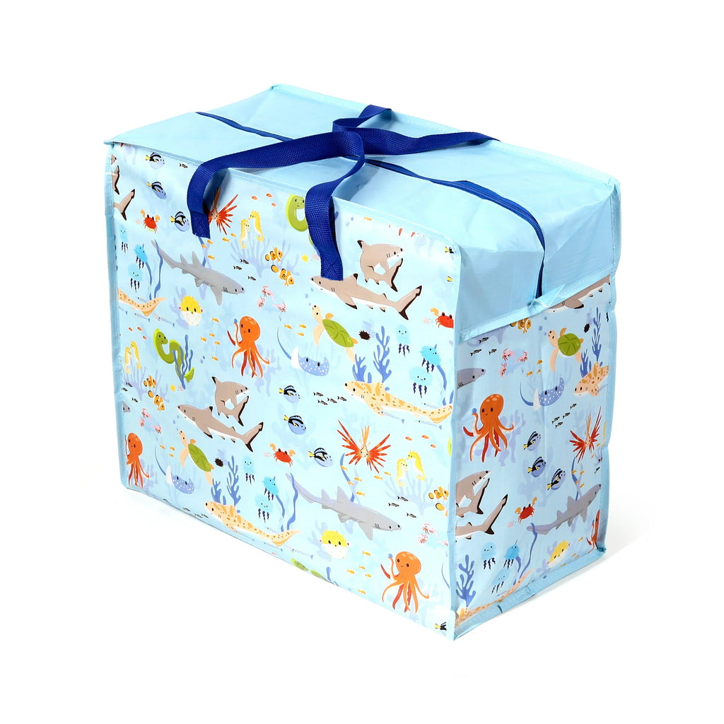 Angled view of a light blue laundry and storage bag, featuring a colourful 'Mariniverse' pattern of sharks, octopuses, jellyfish, and various other sea creatures. The bag has dark blue fabric handles tied on top and a visible zip closure.