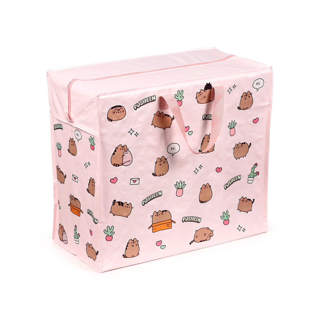 Pink laundry and storage bag, shown from an angled view, featuring a repeating pattern of brown cartoon cats, green potted plants, hearts, and the word 'Pusheen', with pink fabric handles and a top zip closure.