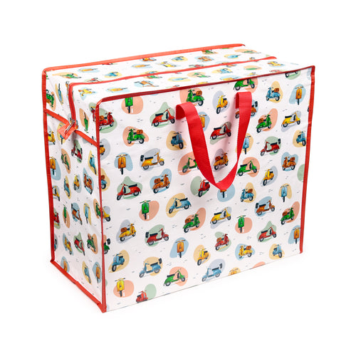 Angled view of a white, rectangular laundry and storage bag with red webbing handles and a red zip closure, featuring a vibrant, all-over pattern of various colourful scooters in red, green, blue, yellow, and orange.