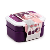 Angled view of a dark purple bento clip lock lunch box with a white lid, featuring a pink and purple Moomin-themed packaging band. The band illustrates two Moomin characters on a bench and highlights dual compartments and included cutlery.