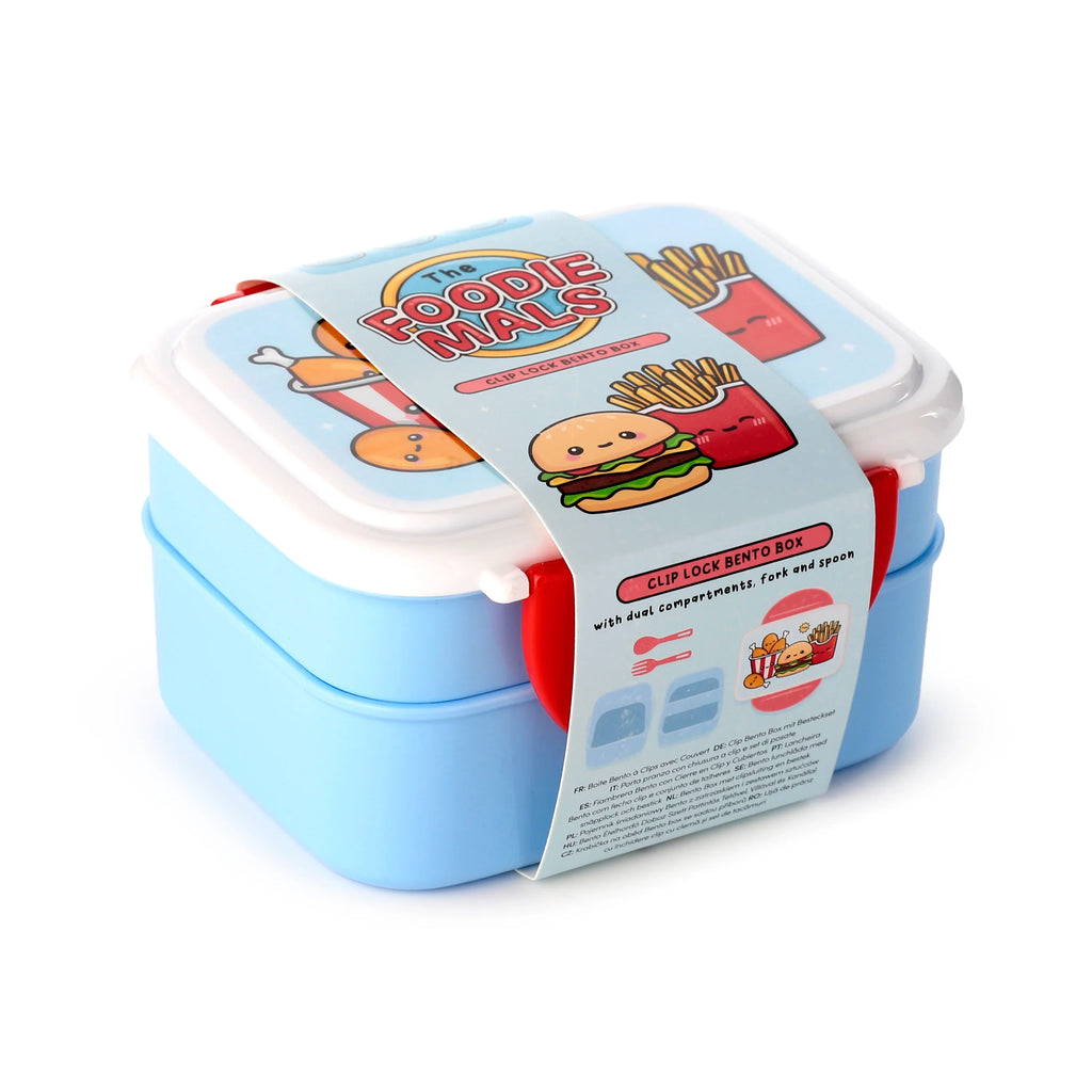 Angled view of a light blue and white bento clip lock lunch box. It features red clip locks and a decorative paper band displaying 'Foodiemals' text alongside cartoon illustrations of a burger, chips, and chicken drumstick. The band also indicates the box includes dual compartments and cutlery.