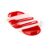 Angled view of an open white and red Bento clip lock lunch box, revealing a red spoon and fork cutlery set inside.