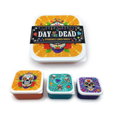 Set of three stackable lunch boxes, angled view displaying vibrant Day of the Dead sugar skull designs on their lids, with orange-brown, blue, and purple bases, in large, medium, and small sizes.