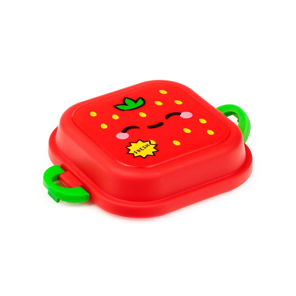 An angled view of a red strawberry-design bento snack lunch box, featuring a smiling cartoon face, 'FRESH' label, yellow dots, green leaf stem, and green clip locks on the sides.
