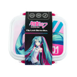 Front view of a white bento lunch box featuring Hatsune Miku character artwork on a black packaging sleeve, with pink clip locks.