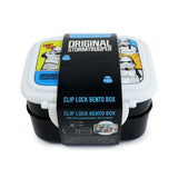 Angled front view of a white and black clip lock bento lunch box. The white lid displays comic-style Stormtrooper illustrations, while a black packaging band indicates it has dual compartments and includes a fork and spoon.
