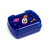 Angled view of a dark blue lunch box, its lid decorated with a space-themed illustration featuring a white and red rocket with a person's face in the window, a pink ringed planet, a yellow shooting star, and various small stars.
