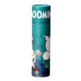 Front view of a Moomin paper stick lip balm, featuring a teal-coloured tube with a white Moomin logo, an illustration of Moomin characters, yellow flowers, and green foliage.