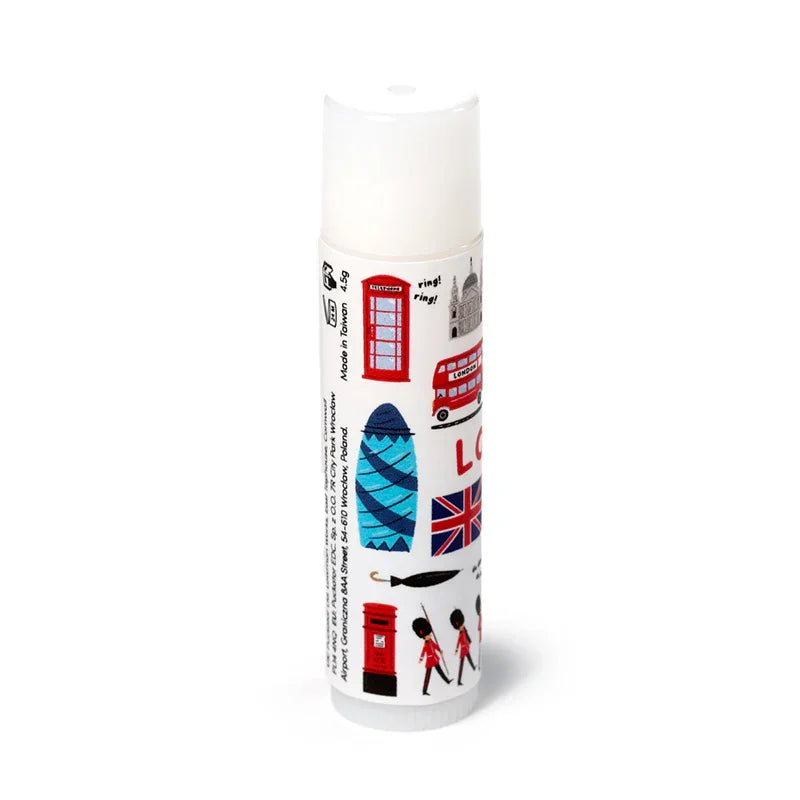 Angled view of a white stick lip balm tube, decorated with various colourful London souvenir illustrations including a red telephone box, a double-decker bus, and the Union Jack flag.