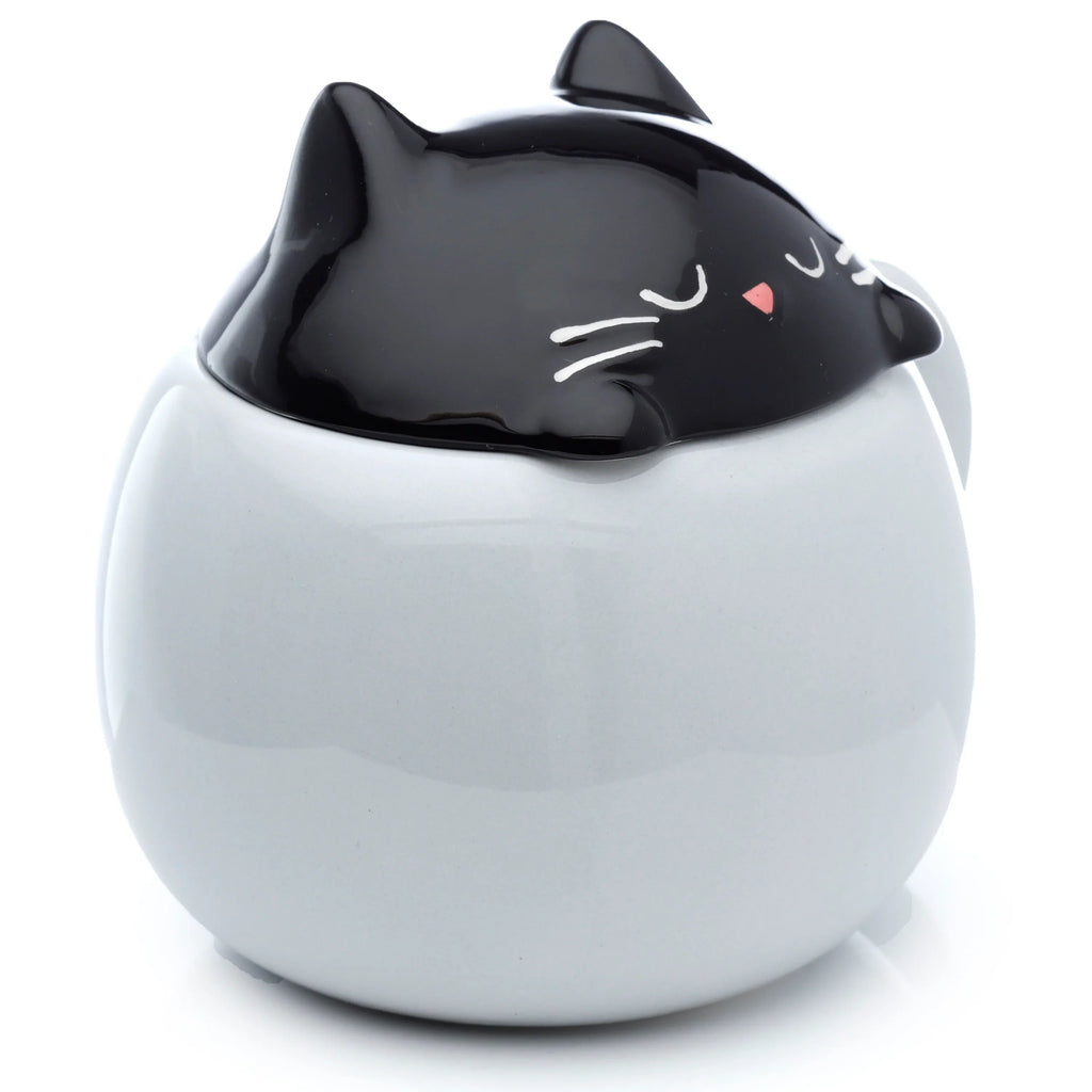 Angled front view of a ceramic lidded mug with a rounded light grey body. The black cat-shaped lid features closed eyes, a pink nose, and white whiskers.