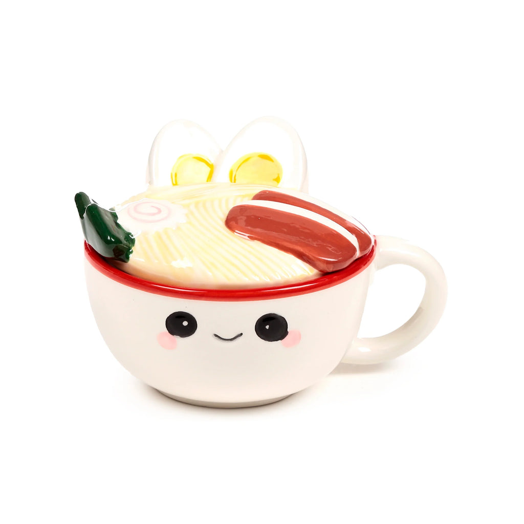 Front view of a white ceramic lidded mug with a smiling face and red rim, topped with a ramen noodle design lid featuring egg halves, narutomaki, meat slices, and a green garnish.