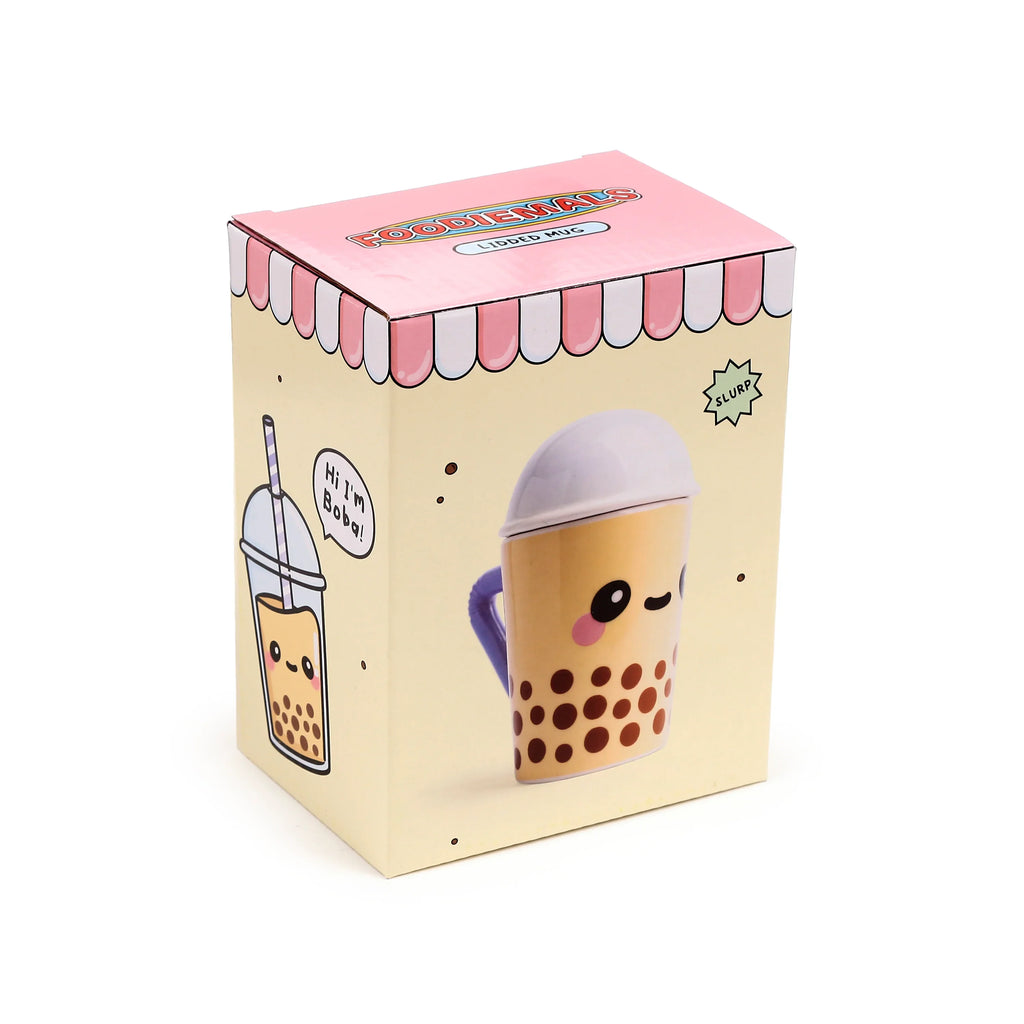 Angled view of a pale yellow and pink product box for a ceramic lidded mug, illustrated with a cartoon boba tea character featuring a light purple lid and handle, and 'Foodiemals Lidded Mug' text.