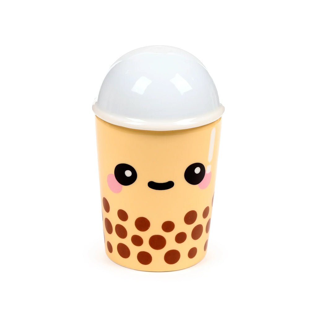 Front view of a pale yellow lidded mug, designed like a kawaii bubble tea cup with a smiling face, pink cheeks, a white domed lid, and brown boba patterns.