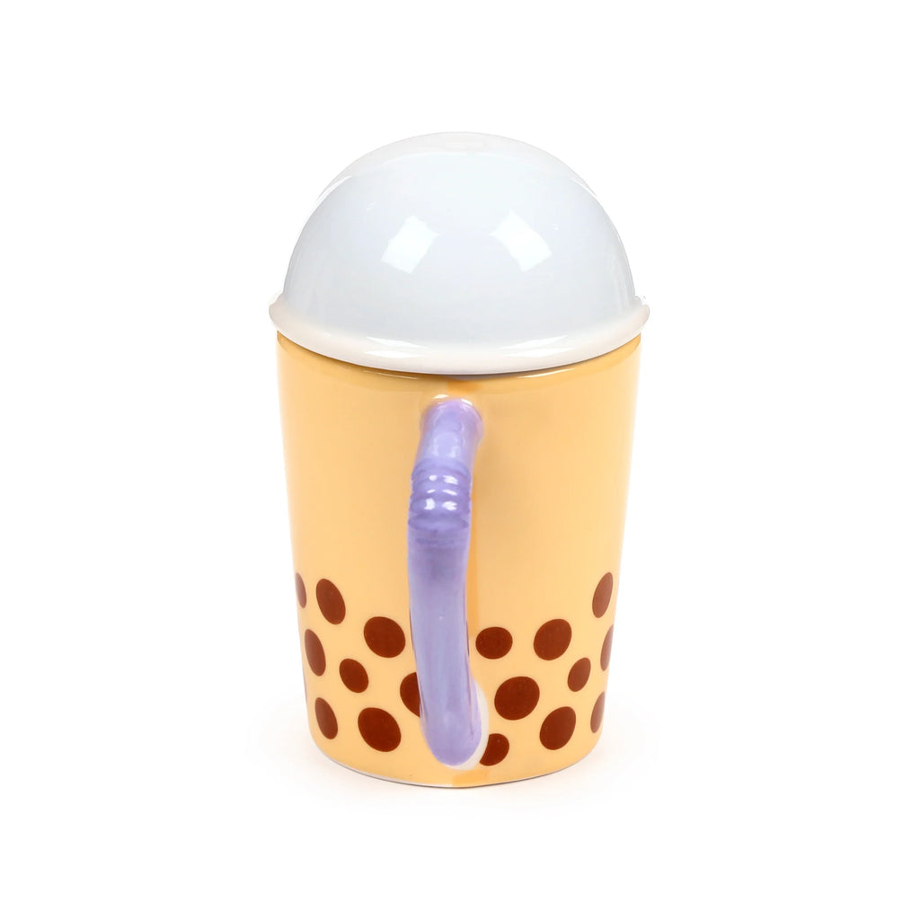 Side view of a pale yellow ceramic lidded mug, decorated with dark brown spots. It features a purple ribbed handle and a white domed lid.
