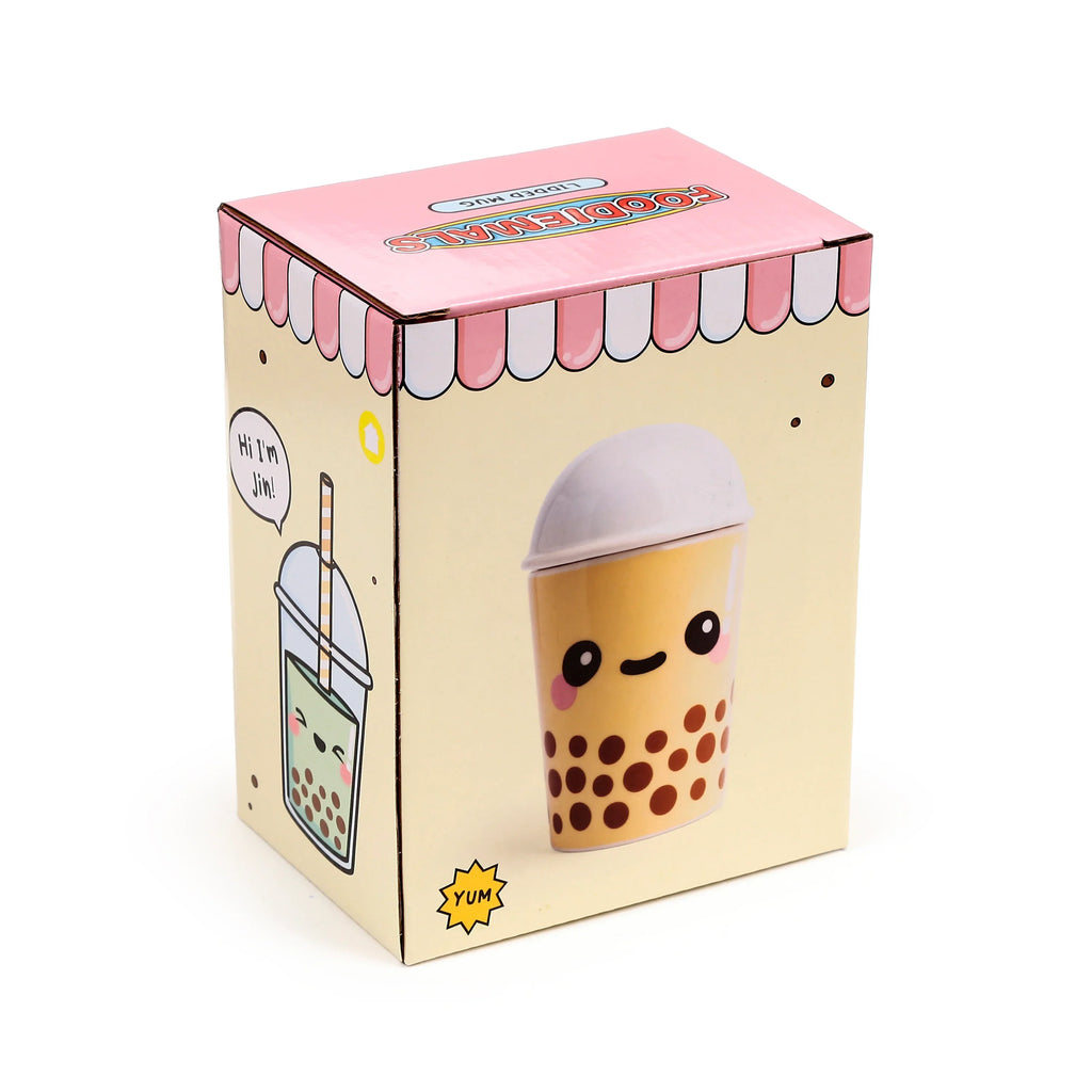 Angled view of a light yellow packaging box for a Boba the Bubble Tea Foodiemals ceramic lidded mug, featuring pink and white striped awning details on the top and cartoon illustrations of bubble tea characters on its visible sides.