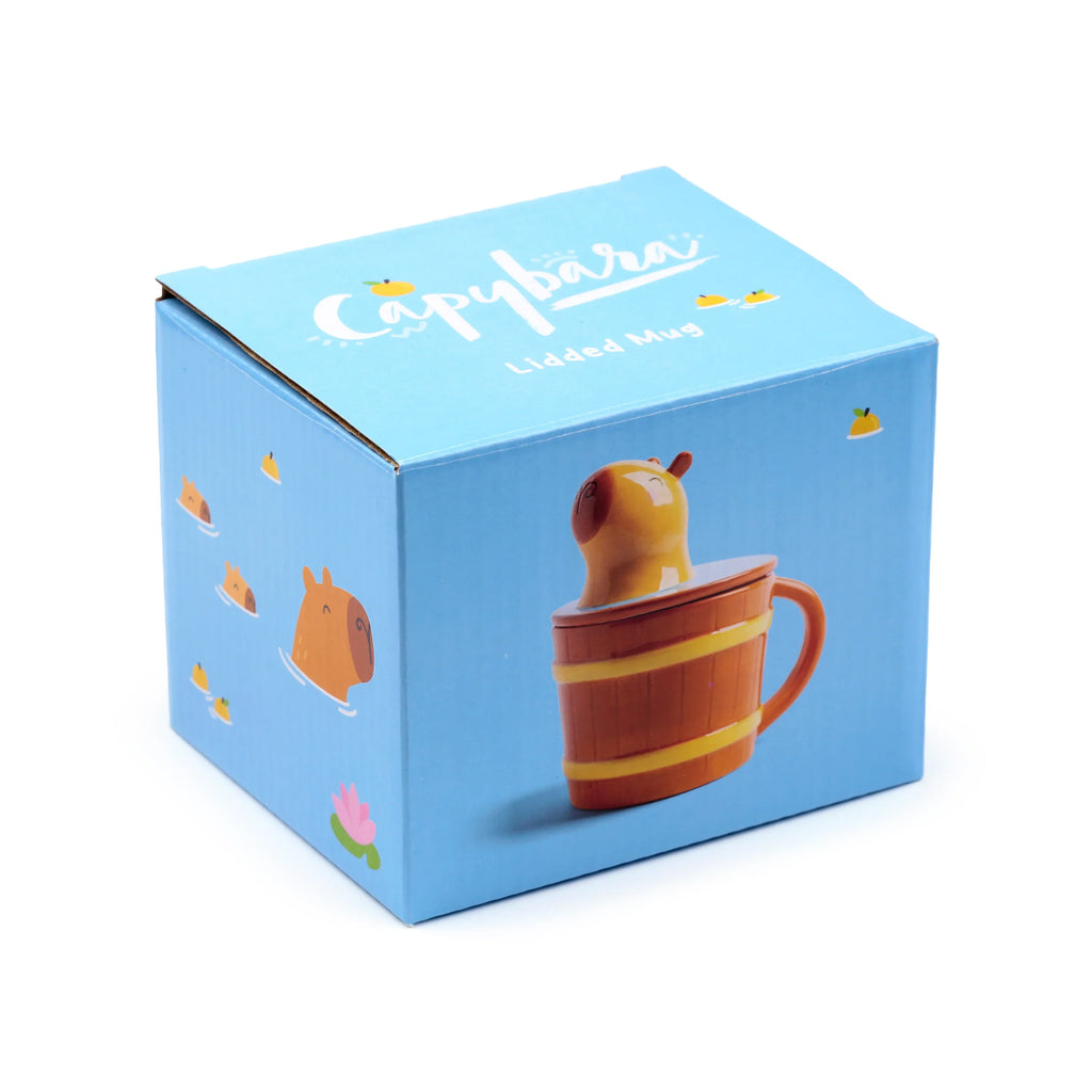 Angled view of a light blue packaging box for a ceramic lidded capybara mug, featuring illustrations of the barrel-shaped mug and swimming capybaras.