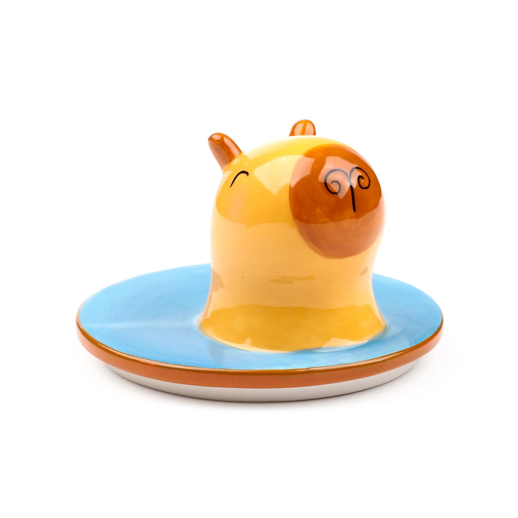 Angled view of a ceramic lidded mug, featuring a smiling yellow and brown capybara head as the lid, set upon a light blue mug base with a brown rim.