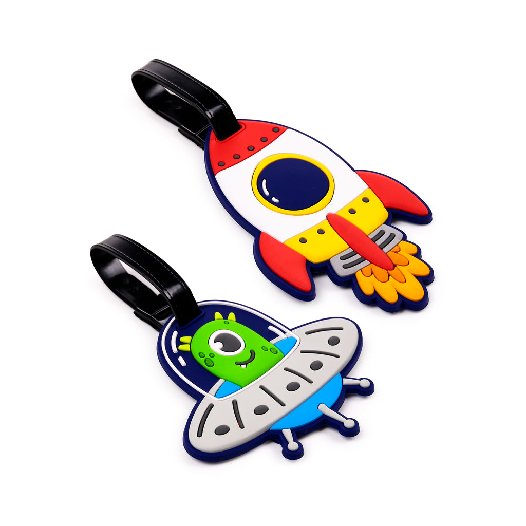 Angled overhead view of two colourful PVC luggage tags. One is shaped like a red, white, and blue rocket, the other a grey and blue flying saucer with a green alien.