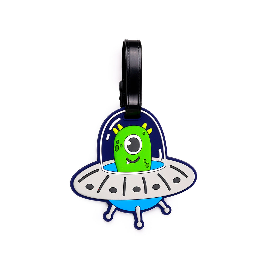 Front view of a PVC luggage tag shaped like a blue and grey flying saucer with a green alien inside, featuring one large eye and a smiling mouth, and a black attachment strap.