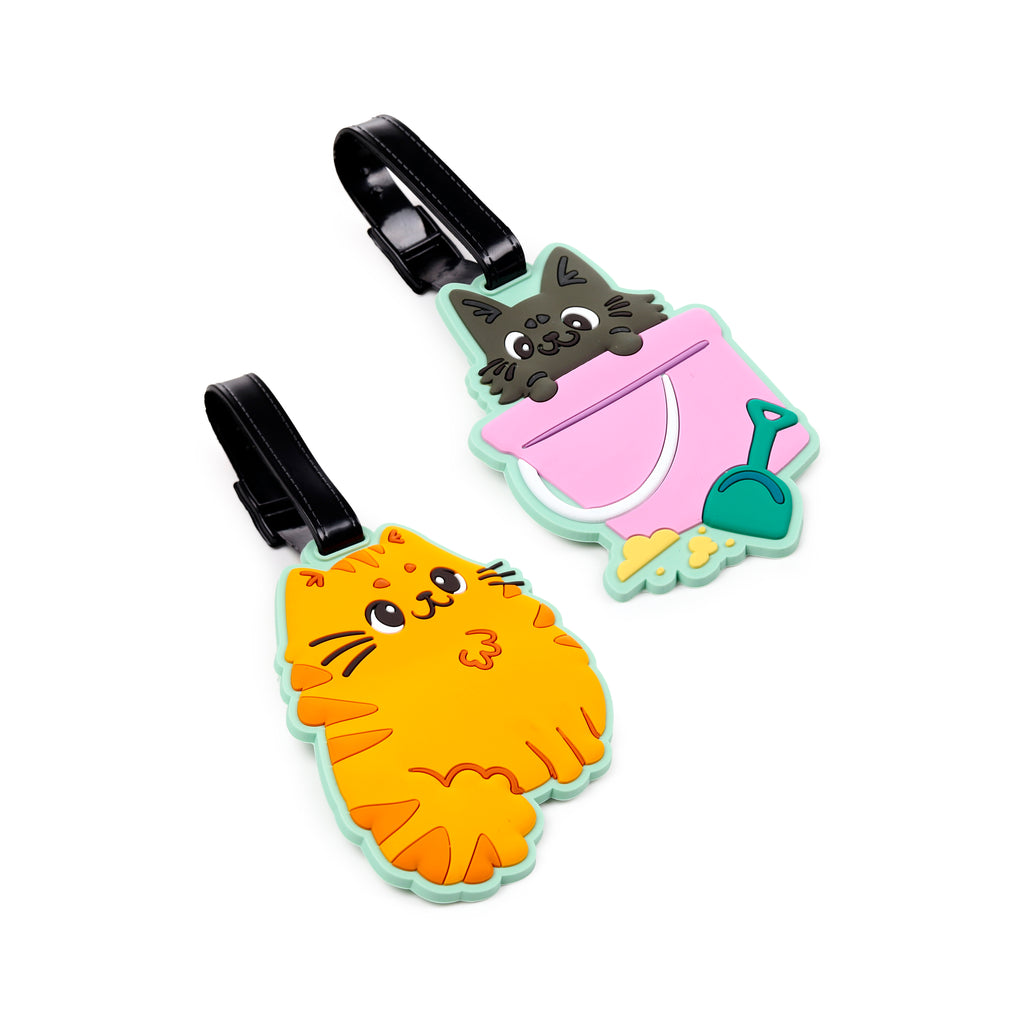 Angled view of two colourful PVC luggage tags. One tag features a cheerful orange tabby cat with black stripes and whiskers. The second tag shows a grey cat poking its head out from a pink bucket, complete with a green spade. Both tags are outlined in light green and have black strap buckles.