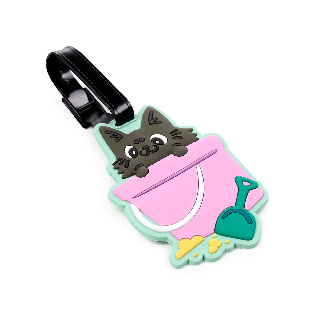 Colourful PVC luggage tag depicting a grey cat peeking from a pink bucket, with a green spade and yellow sand details, featuring a black attachment strap.