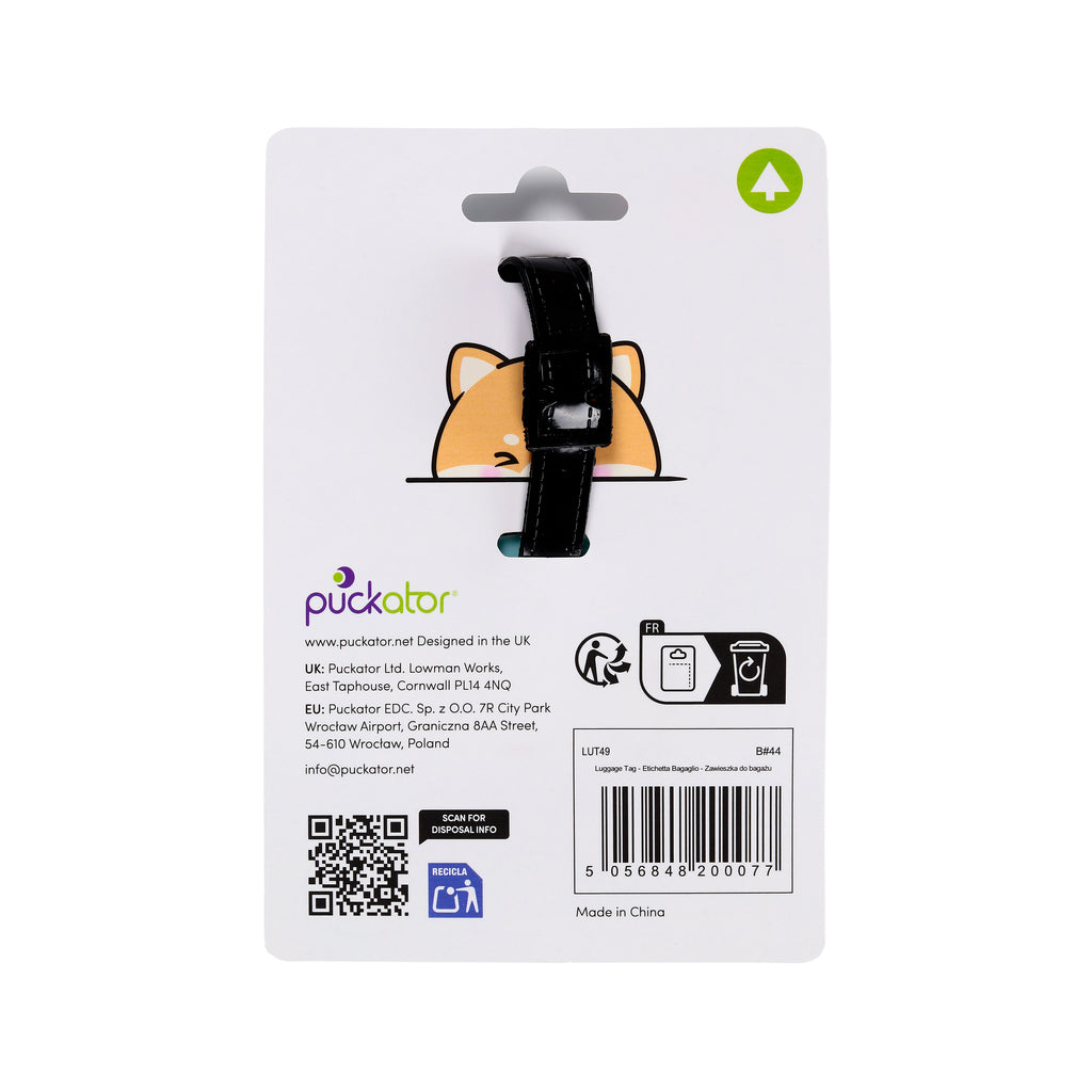Back of white retail packaging for a PVC luggage tag, featuring an orange and white cartoon Shiba Inu dog design visible through a cutout, held by a black strap with a buckle. The packaging also displays a barcode, QR code, and recycling symbols.