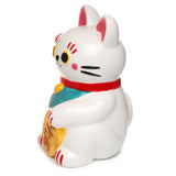 Angled view of a white ceramic Maneki Neko lucky cat money box, showing its left side. It features a red collar, red inner ears, black and yellow eyes, red markings above its eyes, pink cheeks, and black whiskers. The sitting cat holds a gold-coloured coin with brown characters, and its paws have red stripe details.