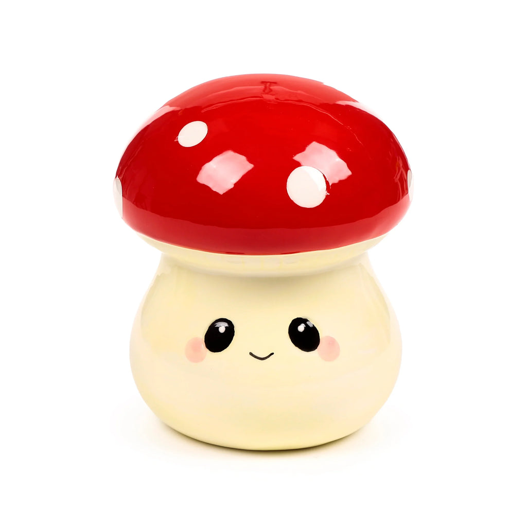 Front view of a ceramic mushroom money box, featuring a shiny red cap with white spots and a creamy yellow base with a smiling face, black eyes, and pink cheeks.
