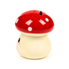 Angled view of a cute ceramic mushroom money box, featuring a shiny red cap with white spots, a cream stem, a coin slot on top, and a black eye with pink blush detail on the side.