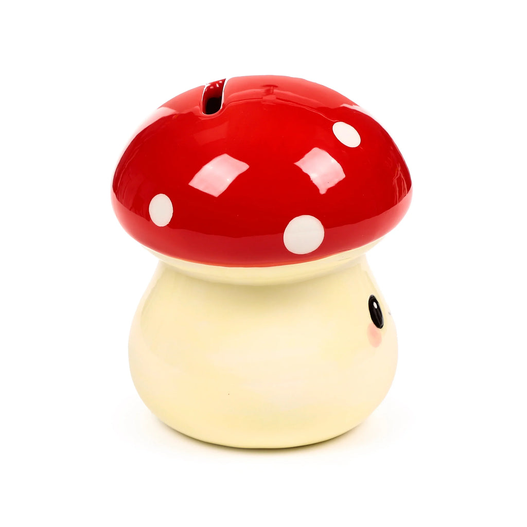 Front view of a cute ceramic mushroom money box, featuring a glossy red cap with white spots, a creamy stalk with a sweet face, and a coin slot on top.