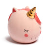 Angled view of a pink ceramic unicorn money box featuring a golden horn, dark pink mane, closed eyelashes, and rosy cheeks.