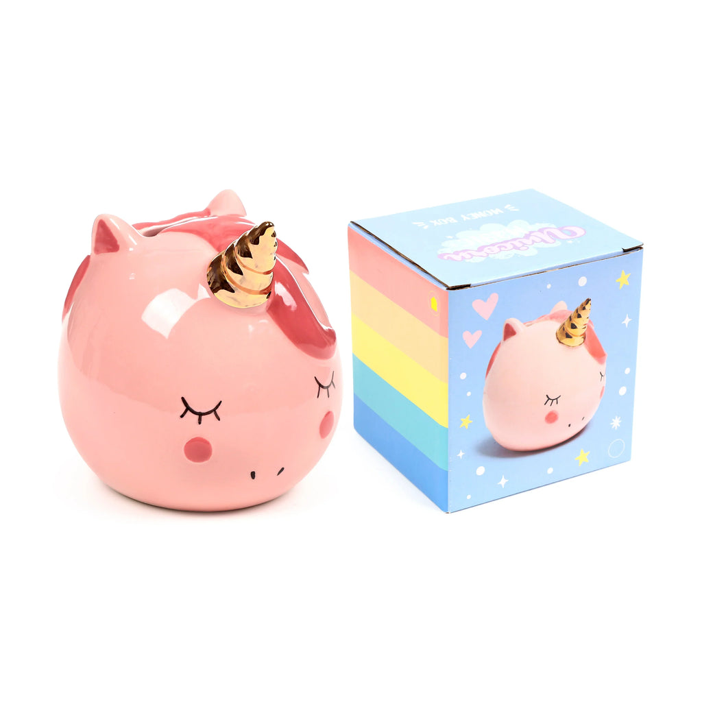 Angled view of a pink ceramic unicorn money box with a gold horn, closed eyes, and rosy cheeks, positioned beside its colourful rainbow-striped packaging box, which features a similar unicorn design.