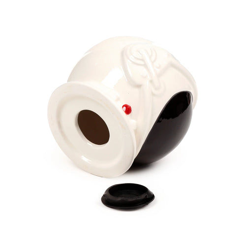Angled view of a white and black ceramic astronaut helmet money box with a red button detail, showing its base coin retrieval opening and the separate black rubber stopper.