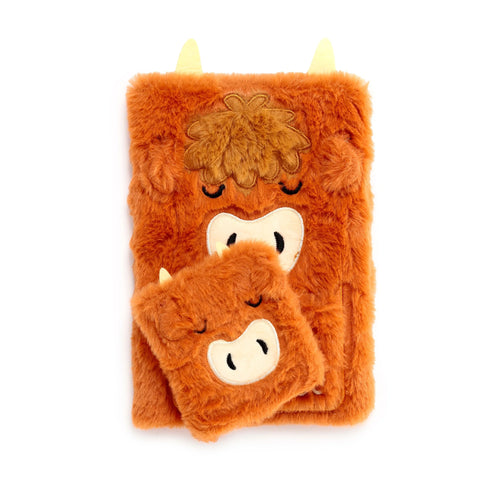 Front view of a plush orange Highland Coo A5 notebook with a smaller, matching mini notebook, both with embroidered faces and yellow horns, on a white background.