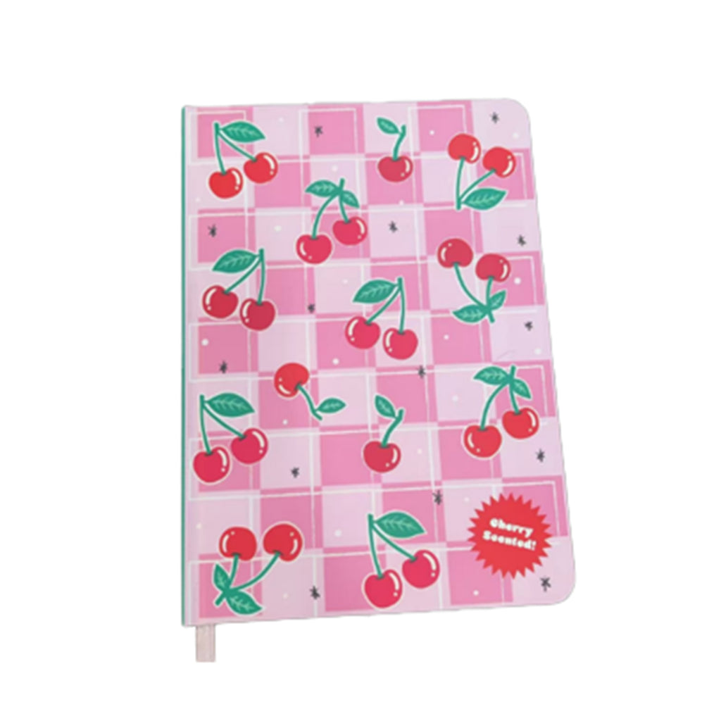 Angled view of an A5 notebook featuring a pink chequered cover with repeated illustrations of red cherries with green stems and leaves, and small black star details. A red starburst design is visible in the bottom right corner, and a bookmark ribbon protrudes from the bottom edge.