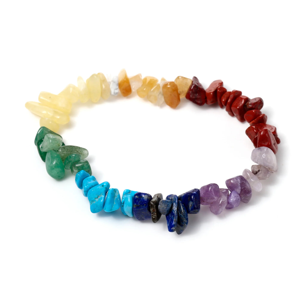 Overhead view of a gemstone chakra bracelet made of colorful irregular chip stones, arranged in a rainbow pattern on a white background.