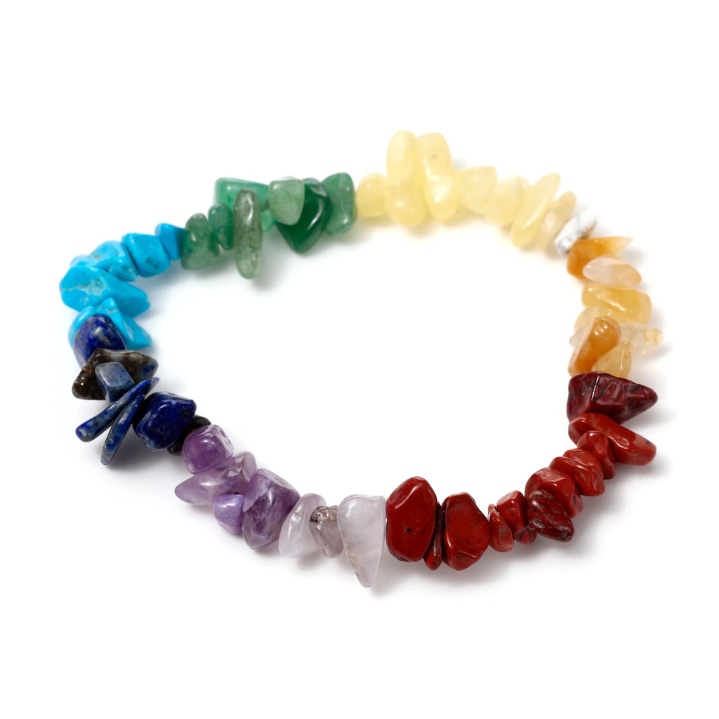 Top-down view of a gemstone chakra bracelet featuring tumbled stones in a rainbow gradient of red, orange, yellow, green, blue, and purple, isolated on a white background.