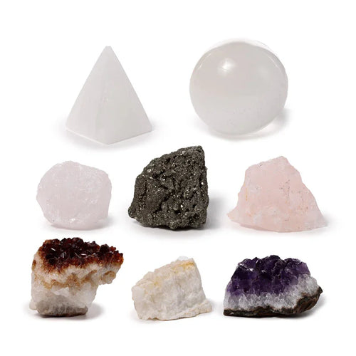 Assortment of seven crystals on white: white pyramid, clear spherical crystal, two rough pale pink rose quartz pieces, dark grey pyrite nugget, orange-brown citrine cluster, white rough crystal, purple amethyst cluster.
