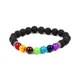 Angled view of a chakra lava rock gemstone bracelet, comprising porous black lava rock beads and seven smooth colourful beads, including red, yellow, brown, green, turquoise, dark blue, and purple, accented with silver-coloured ridged spacers.