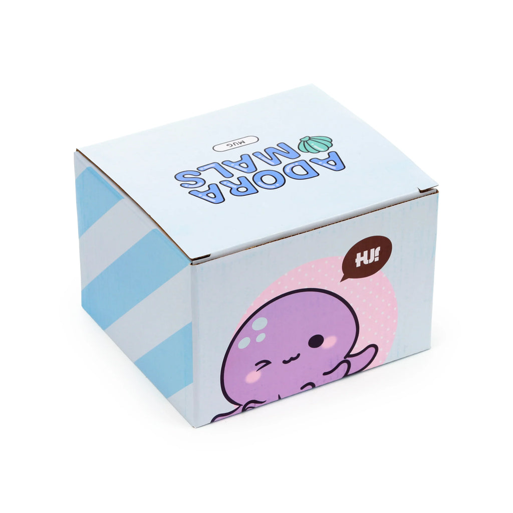 Angled view of a mug box for the Adoramals Octopus Head ceramic mug. The box displays 'ADORAMALS MUG' text and a green seashell on top, a purple octopus character with a 'HI!' speech bubble on the front, and light blue and white stripes on the side.