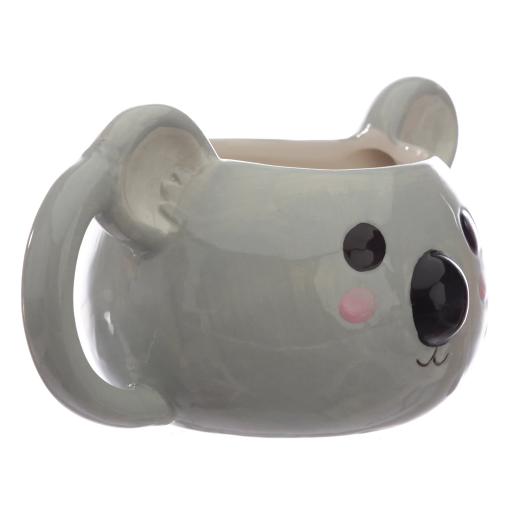 Angled view of a grey ceramic koala shaped mug, featuring black eyes, a large black nose, pink cheeks, and an integrated handle on the side.