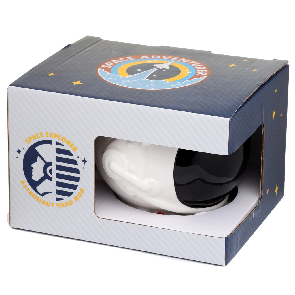 Angled view of a ceramic astronaut space helmet mug, partially visible through a window in its dark blue retail box, which features 'SPACE EXPLORER' and 'ASTRONAUT HEAD MUG' text with a rocket graphic and yellow stars.