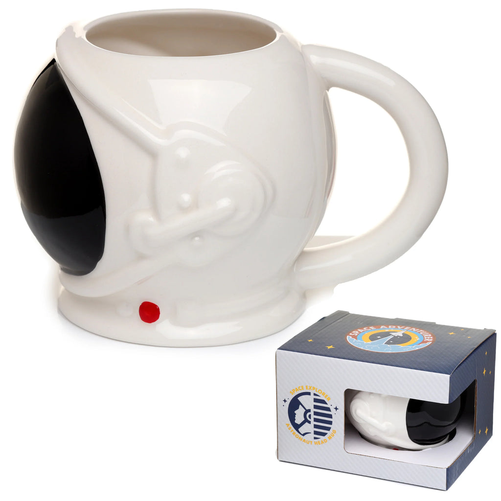 Angled view of a white ceramic astronaut space helmet mug with a black visor and red button detail, presented alongside its blue packaging box.