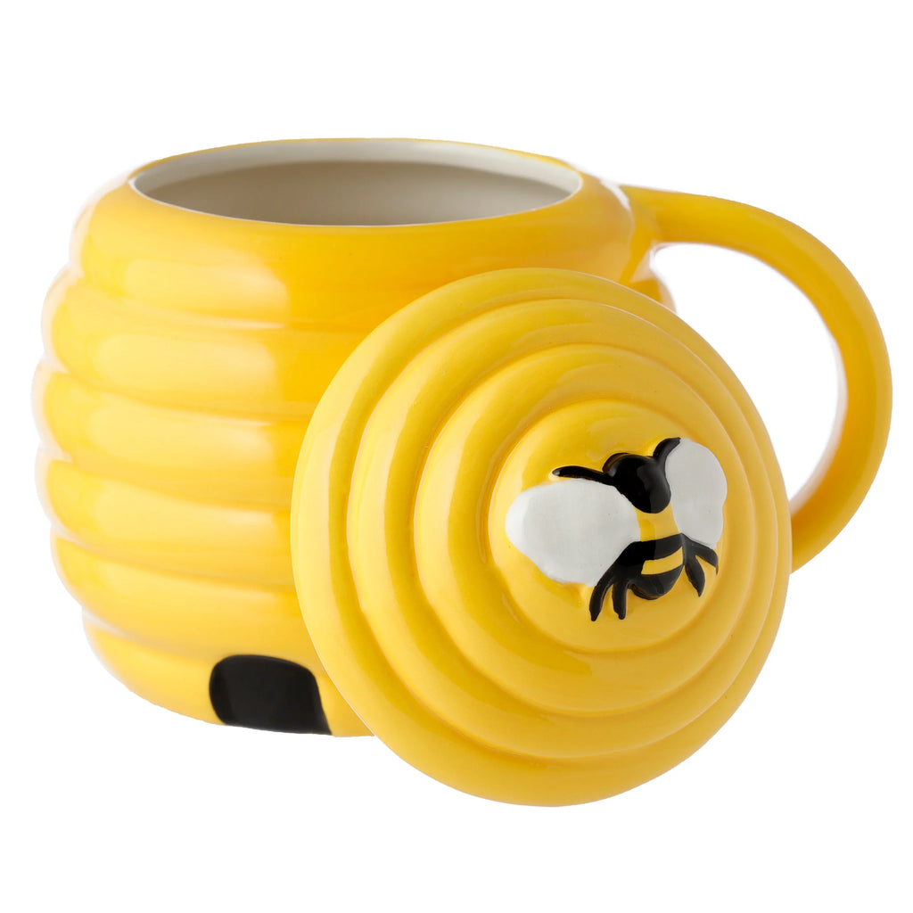 Yellow ceramic beehive mug, angled view, with a ridged body and a lid featuring a bee decoration.